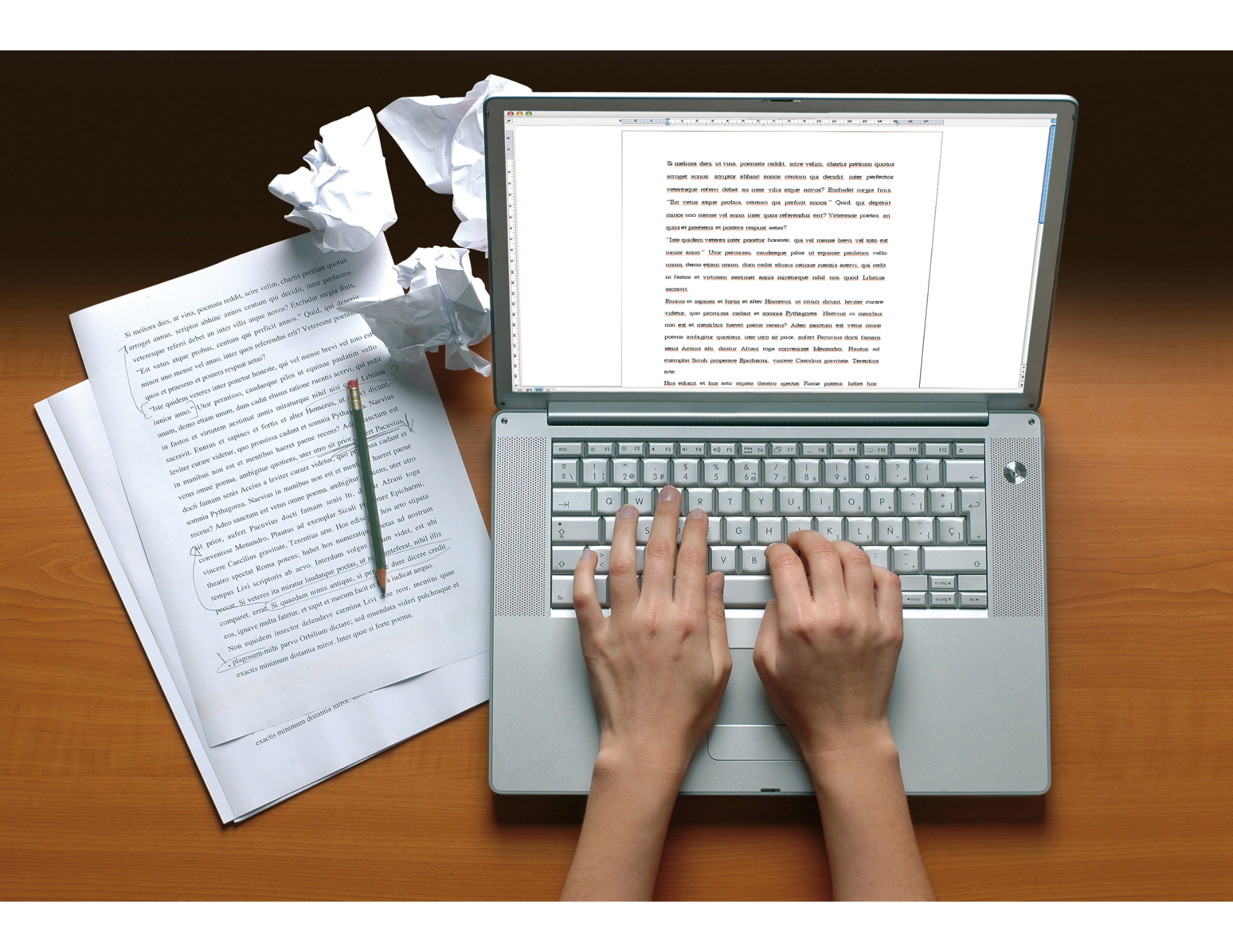 Woman's hands on laptop keyboard with edited manuscript next to her on wooden table. Writing retreats at Terre Haute Farm Retreat Center near Richmond Va.