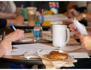 Hands on table writing with water bottles and cups at writers retreat at Terre Haute Retreat Center. 