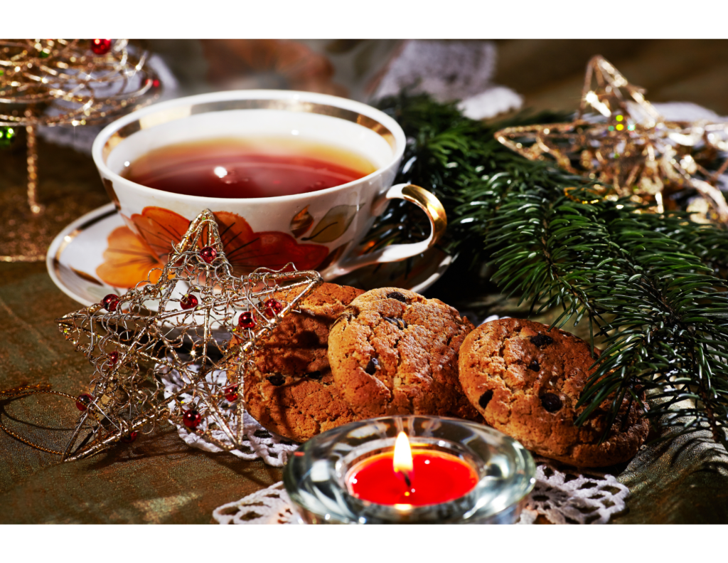 Cip of tea with holiday cookies, red candle and pine decoration